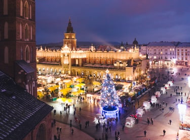 Krakow Main Market Square at night featuring the Christmas market, illuminated Cloth Hall, and festive tree.