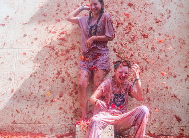 Two happy women covered in red pulp during the La Tomatina tomato festival in Spain.