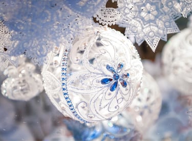 Elegant white glass Christmas ornament with blue crystal floral details and lace snowflakes.