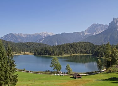 Scenic view of Lautersee lake in the Bavarian Alps with pine forests and jagged mountain peaks.