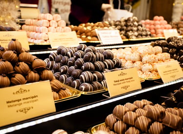 Assorted gourmet marzipan pralines and chocolate truffles displayed at a European Christmas market.