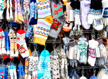 Display of colorful handmade wool socks and knitted mittens with Nordic patterns at a winter market.