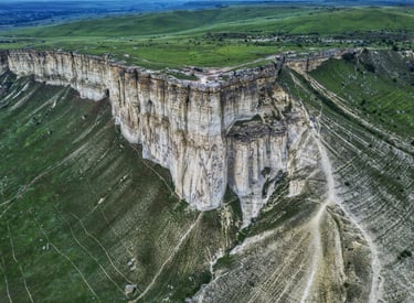 Aerial view of the massive White Rock limestone cliff formation in a green valley landscape.