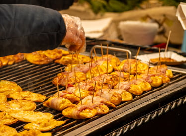 Grilled oscypek smoked sheep cheese wrapped in bacon at a traditional Polish Christmas market stall.