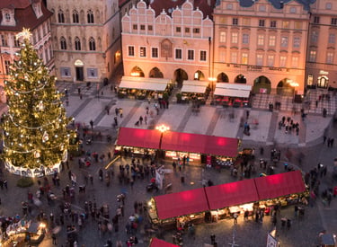 Aerial view of the Prague Christmas market in Old Town Square with a lit tree and festive stalls.