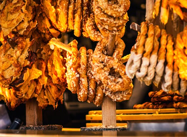 Freshly baked German pretzels and sweet pastries with almond flakes on wooden display stands at a market.