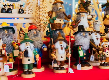 Handcrafted German incense smoker dolls and wooden nutcrackers at a traditional Christmas market.