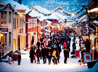 Crowds walking through a snowy European Christmas market street with festive lights and winter decorations.