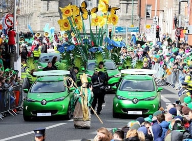 St. Patrick's Day parade in Dublin featuring green Renault Zoe electric cars and flower floats.