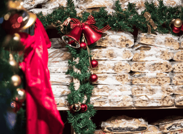 Shelves of wrapped German Christmas stollen and poppy seed cakes at a festive holiday market stall.