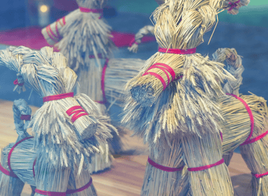 Traditional Swedish Yule Goat figurines made of straw and red ribbons on display in a window.