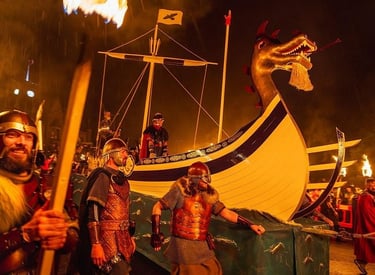 Vikings in traditional armor pulling a wooden longship during the Up Helly Aa fire festival.