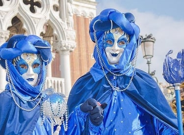 Two performers wearing ornate blue costumes and masks at the Carnival of Venice in Italy.