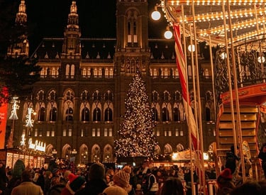 Crowds at the Vienna Christmas Market at Rathausplatz with a lit tree and carousel.