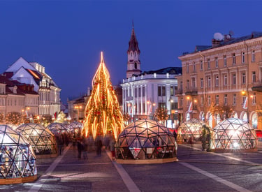 Christmas market at night in Vilnius, Lithuania, featuring a glowing tree and glass igloo domes.