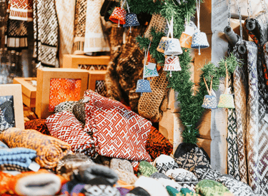 Traditional knitted wool mittens and sweaters with Nordic patterns at a festive outdoor Christmas market stall.