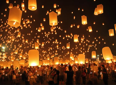 Hundreds of glowing paper lanterns released into the night sky during a traditional Yi Peng festival celebration.