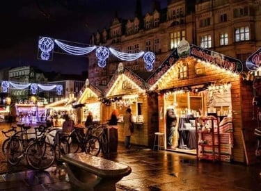 Festive wooden stalls and glowing lights at the Sheffield Christmas Market at night.