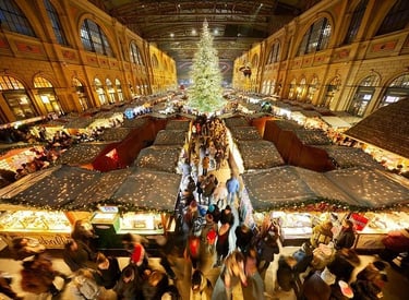 Crowded indoor Zurich Christmas market at the main train station featuring a tall illuminated tree and stalls.