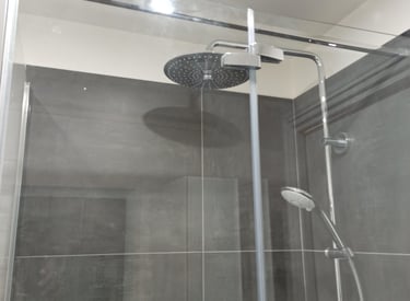Douche de salle de bain moderne avec grande tête de pluie et douchette à main sur carrelage gris fon