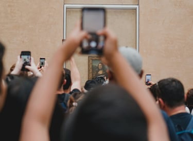 Photo by Tarik on Unsplash מבקרים ממיפים את הסמרטפון מעל ראשיהם כדי לצלם את ציור המונה ליזה .