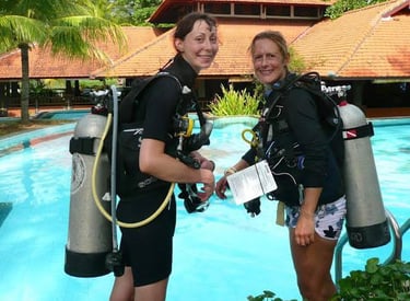 two women in scuba gear standing in front of a swimming pool