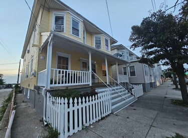 a yellow painted house with a white picket fence
