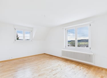 Professionelle Immobilienfotografie: helles Zimmer mit Parkettboden und grossen Fenstern
