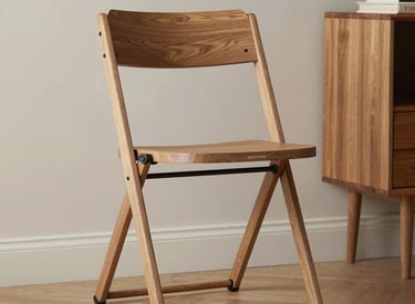 A sleek foldable bed neatly tucked against a wall in a bright, minimalist apartment.