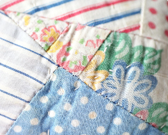 Close-up of vintage patchwork quilt showing aged fabric.