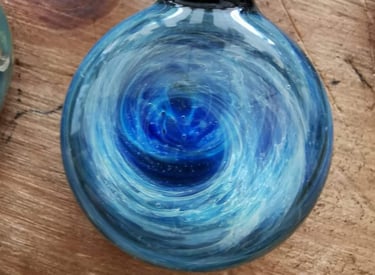 a blue glass pendant necklace with a swirl design