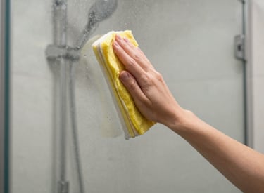 A professional cleaner carefully wiping down a kitchen countertop with a bright smile.