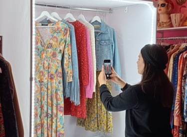  Una mujer usa teléfono inteligente para fotografiar ropa vintage dentro de un estudio profesional