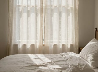 A peaceful North American bedroom scene with premium white linens and a warm, calming ivory light filtering through linen curtains, conveying a sense of restful recovery and nervous system reset.