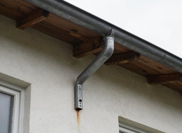 Technician cleaning and repairing gutters on a suburban home.