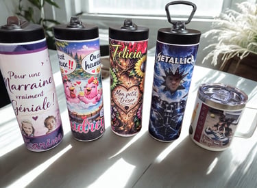 Custom sublimation tumblers and a coffee mug with personalized graphics and photos on a white table.