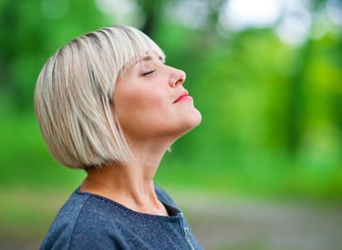 Photo d'une femme qui respire en toute conscience les yeux fermés lors d'une séance de sophrologie
