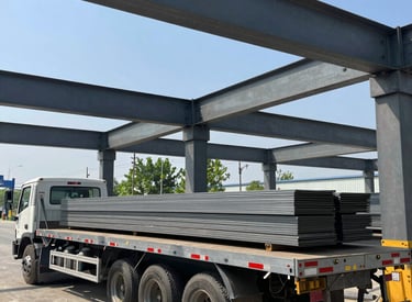 A heavy-duty flatbed trailer loaded with industrial equipment on a highway at sunset.