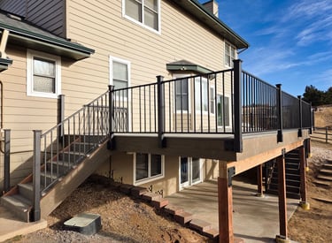 Finished elevated deck with black metal railing and integrated stairs by Elk Valley Contractors.