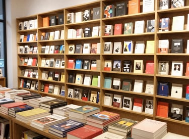 A vibrant display of art books and management titles stacked on a wooden table, showcasing Kalkfell's diverse publishing range.