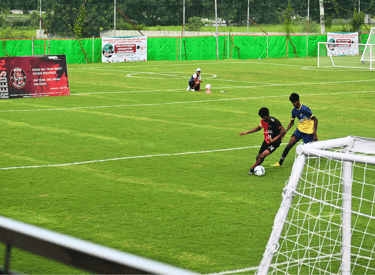 Youth soccer players competing on a green football field during a match at Reeds FC training academy.