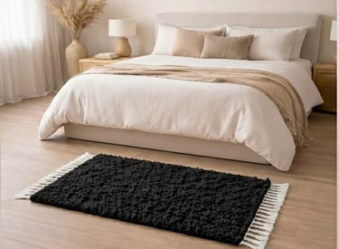 Alfombra de pelo largo con textura negra y flecos blancos sobre en una habitación 