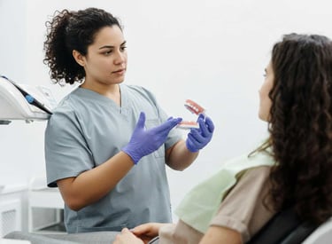 Dentista explicando a paciente sobre las protesis dentales, sosteniendo una protesis dental