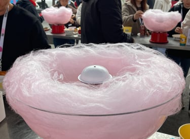 Colorful cotton candy machine spinning fluffy pink cotton candy at a lively family event.