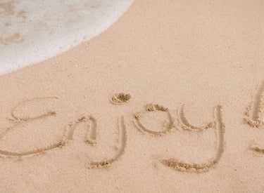 The word ENJOY etched into the sand.