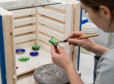 Artist carefully placing glass pieces on a kiln shelf ready for fusing.