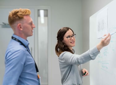 a man and woman standing in front of a white board