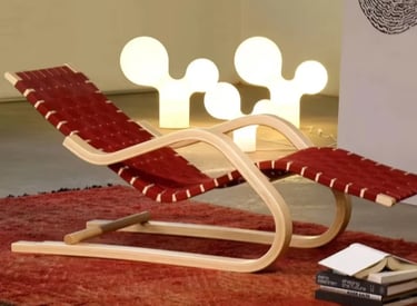 Red woven lounge chair with curved wooden frame, showing Alvar Aalto’s practical furniture for every