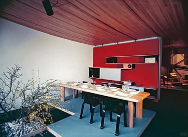 Modern open interior with wooden table, red wall and garden view, inspired by Charlotte Perriand nat