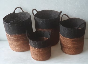 Set of four handmade seagrass storage baskets with handles in a two-tone black and natural brown design.